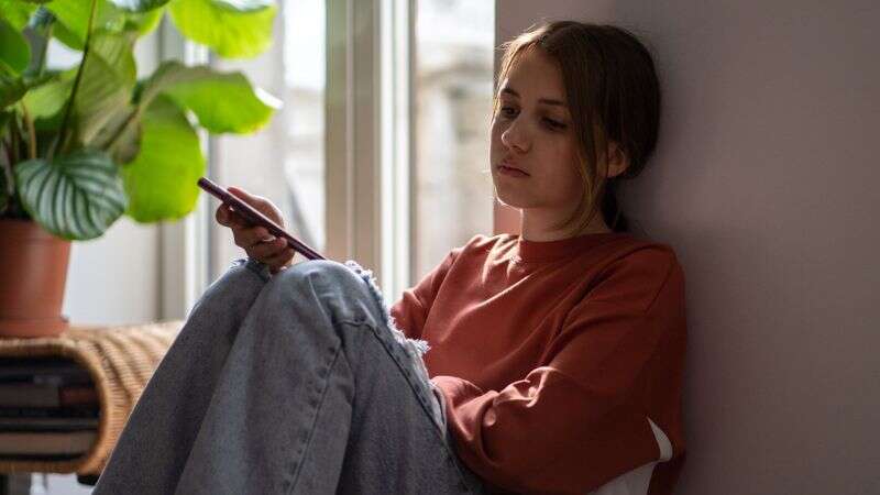 Adolescente triste qui regarde son cellulaire